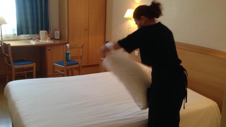Empleada de Grupo SIFU haciendo una cama en la habitación de un hotel