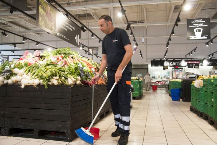Un empleado de Grupo SIFU barriendo en un supermercado