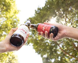 dos personas brindan con cervezas de un pack vermeet