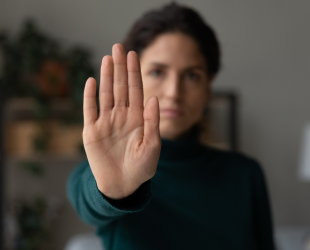 una mujer hace el gesto de 'para' con la mano