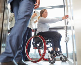 una persona en silla de ruedas se sube a un ascensor en una empresa