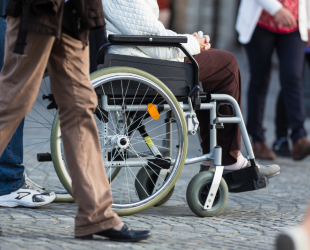 varias personas circulan por la calle, una de ellas en silla de ruedas