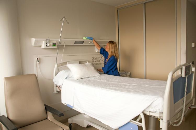 Una empleada de BCL limpiando la barra de suministros de la cama de un hospital
