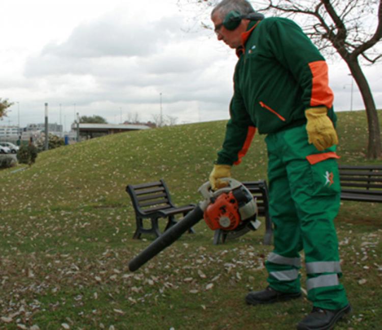 Un jardinero de grupo sifu limpiando una zona verde con un soplador