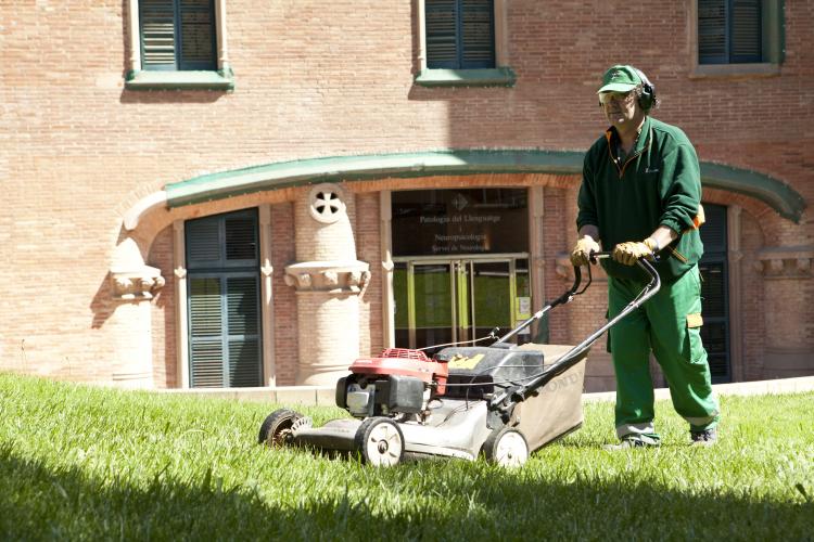 Un jardinero de Grupo SIFU segando el césped de una zona verda