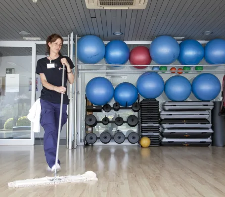Empleada de Grupo SIFU limpiando el suelo de un gimnasio