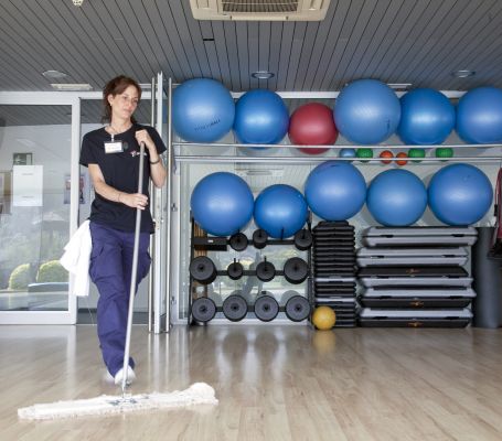 Empleada de Grupo SIFU limpiando el suelo de un gimnasio