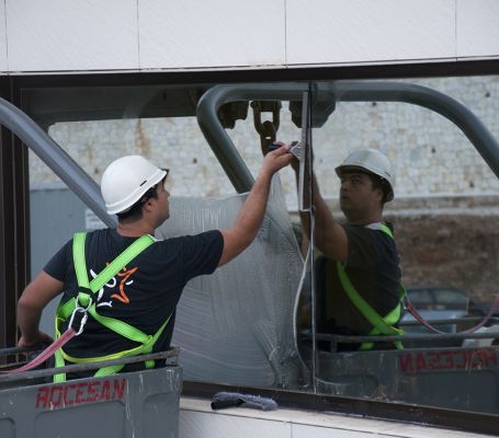 Un operario de Grupo SIFU en una grúa limpiando una ventana de un edificio