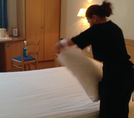 Una empleada de Grupo SIFU preparando una cama en un hotel