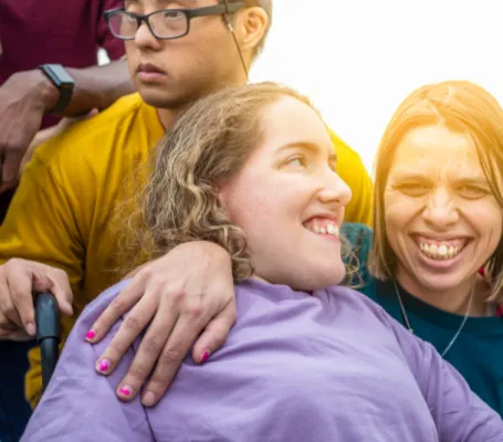 tres personas con discapacidad se abrazan y sonrien