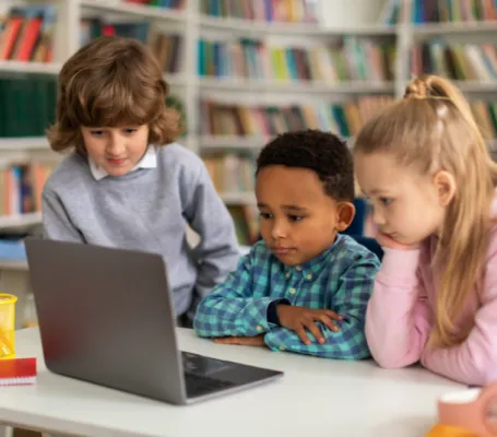 tres niños miran un ordenador en el colegio