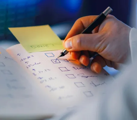 una persona marca un 'hecho' en una lista de tareas escrita en una libreta
