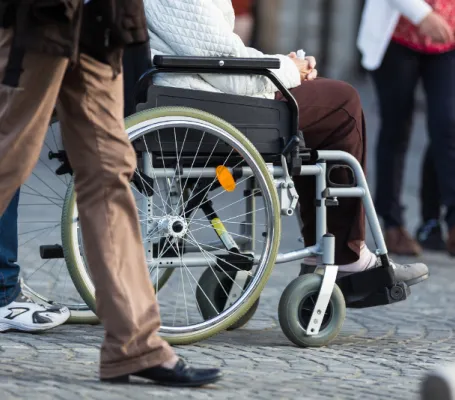 varias personas circulan por la calle, una de ellas en silla de ruedas