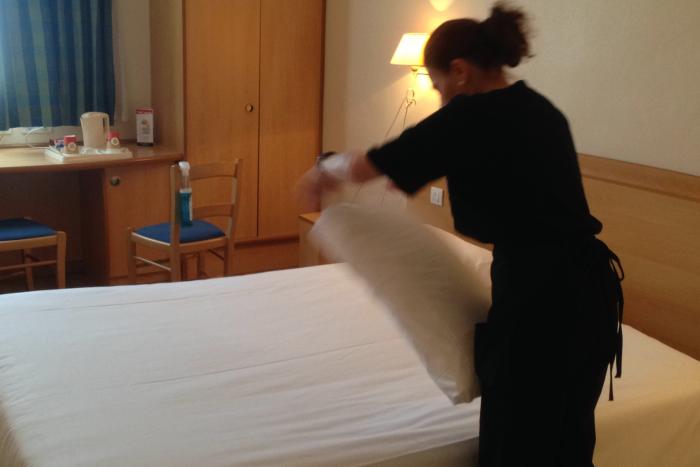 Una empleada de Grupo SIFU preparando una cama en un hotel