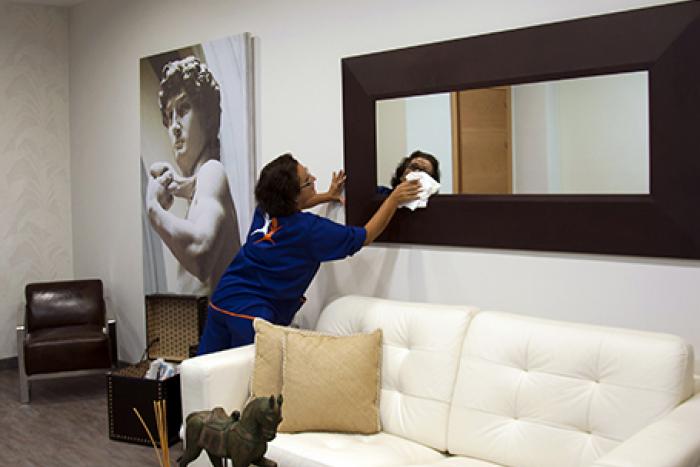 Una empleada de Grupo SIFU limpiando un espejo en la habitación de un hotel